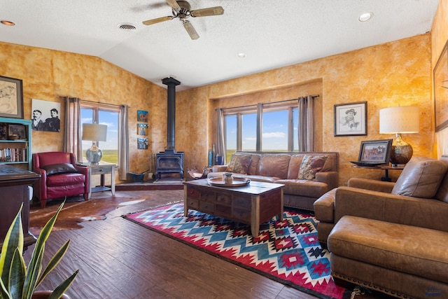 living area with a wealth of natural light, lofted ceiling, a wood stove, and visible vents