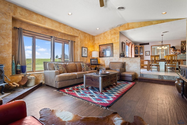 living area with a chandelier, a wood stove, visible vents, and wood finished floors