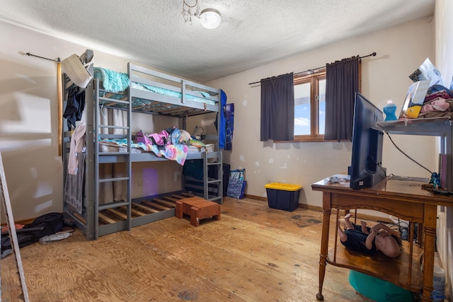 bedroom featuring a textured ceiling, baseboards, and wood finished floors