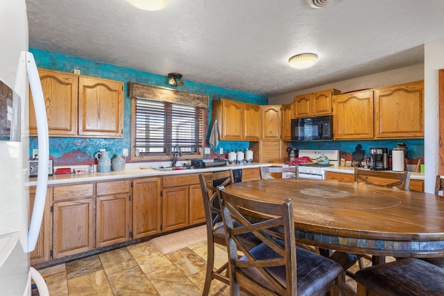 kitchen with white range with gas cooktop, black microwave, light countertops, and a sink