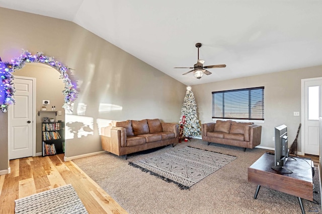 living area with ceiling fan, vaulted ceiling, baseboards, and wood finished floors