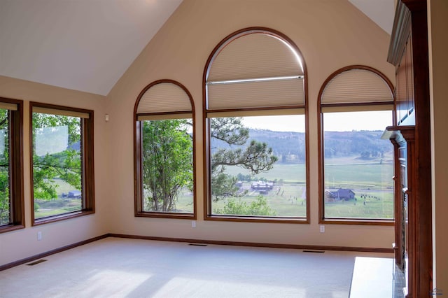 unfurnished room featuring light carpet, high vaulted ceiling, baseboards, and visible vents