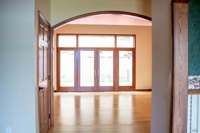 entryway with light wood-type flooring and arched walkways