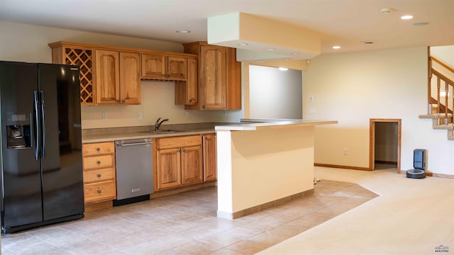 kitchen with brown cabinetry, dishwasher, black refrigerator with ice dispenser, light countertops, and a sink