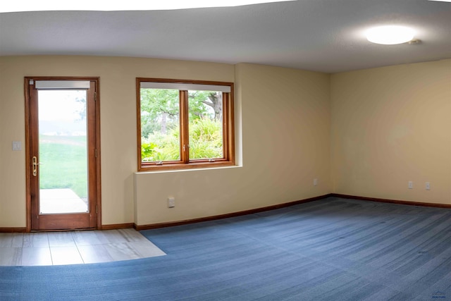 carpeted spare room featuring baseboards