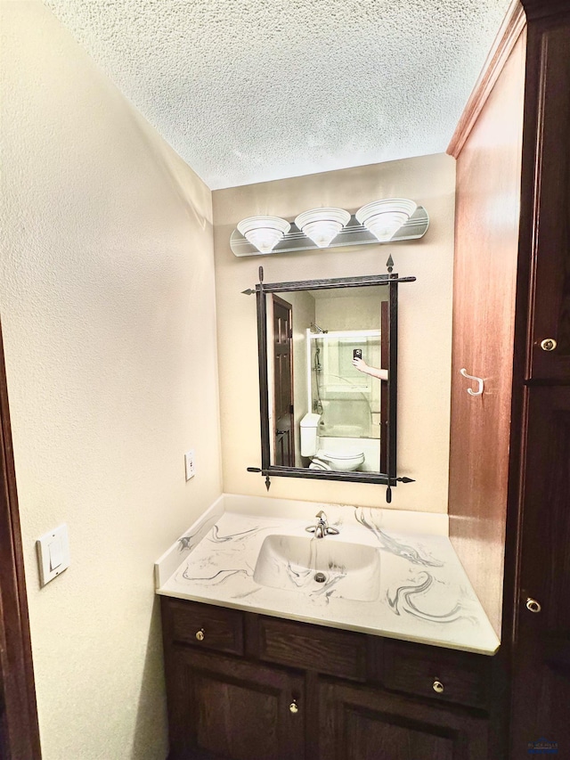 bathroom with a textured ceiling, toilet, and vanity