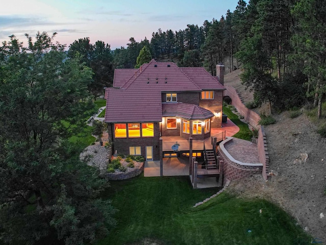 rear view of house featuring a deck, a patio, stairs, a yard, and a chimney