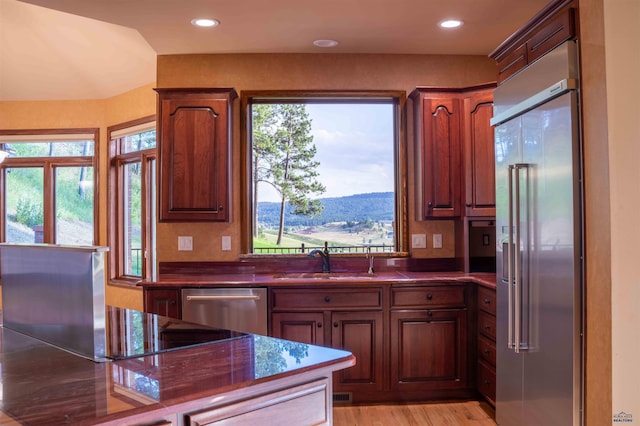 kitchen with light wood-style flooring, a mountain view, recessed lighting, stainless steel appliances, and a sink