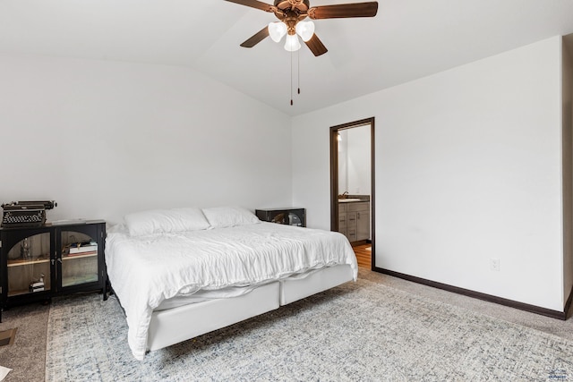 bedroom featuring lofted ceiling, ceiling fan, baseboards, carpet, and ensuite bath