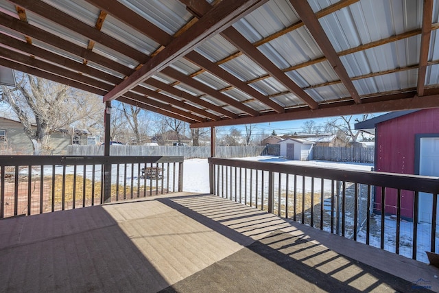 wooden terrace with a storage shed, a fenced backyard, and an outbuilding