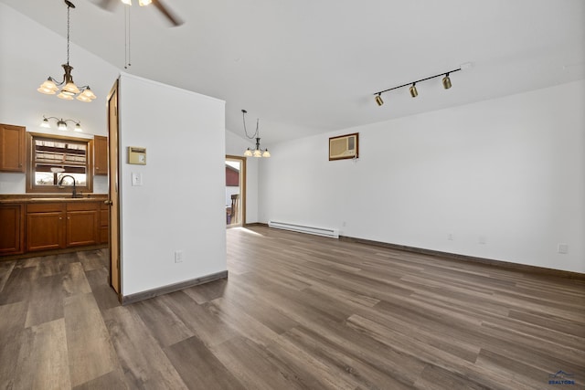 unfurnished living room with dark wood-style flooring, baseboard heating, a sink, a wall mounted air conditioner, and ceiling fan with notable chandelier