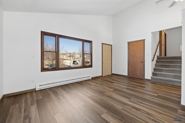 spare room with baseboards, a baseboard radiator, stairway, dark wood-type flooring, and high vaulted ceiling