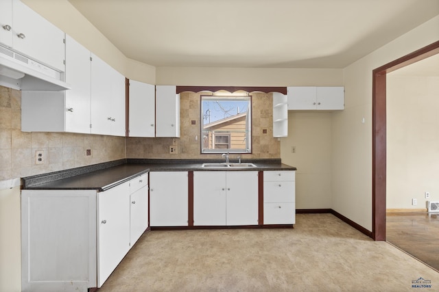 kitchen featuring dark countertops, tasteful backsplash, white cabinets, and a sink