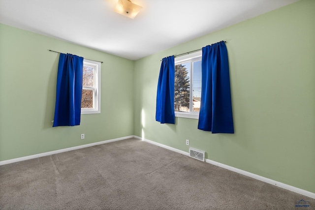 spare room featuring carpet floors, visible vents, and baseboards