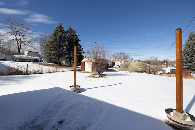 yard layered in snow with an outdoor structure and a storage shed