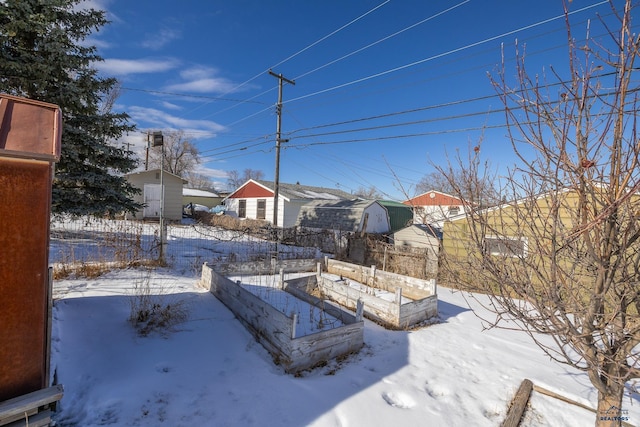 yard layered in snow with a vegetable garden