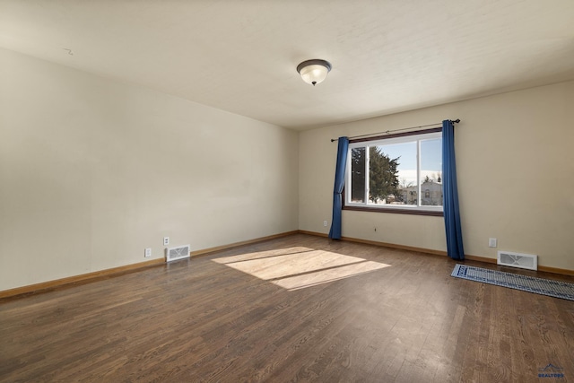 unfurnished room featuring wood finished floors, visible vents, and baseboards