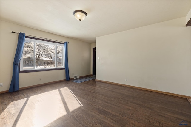 empty room featuring dark wood-style flooring and baseboards