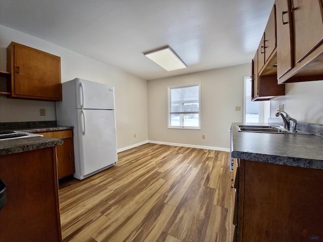 kitchen with dark countertops, a sink, wood finished floors, and freestanding refrigerator