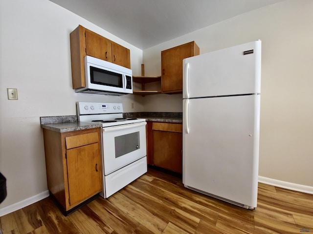 kitchen with dark countertops, white appliances, dark wood-style floors, and brown cabinetry