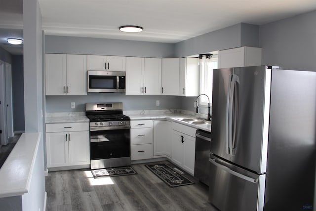 kitchen featuring stainless steel appliances, white cabinets, a sink, and dark wood-type flooring