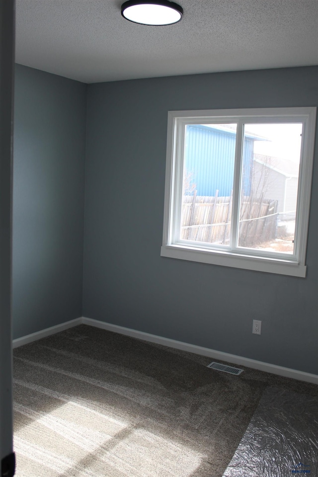 spare room featuring baseboards, visible vents, and a textured ceiling