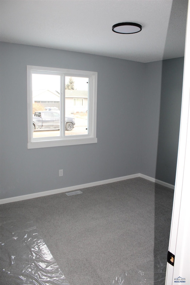 carpeted spare room with visible vents and baseboards