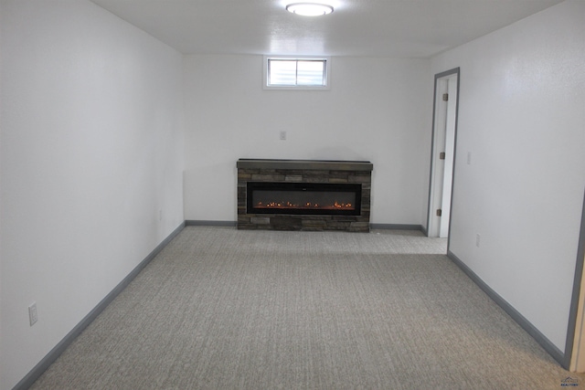 unfurnished living room featuring baseboards, a glass covered fireplace, and light colored carpet