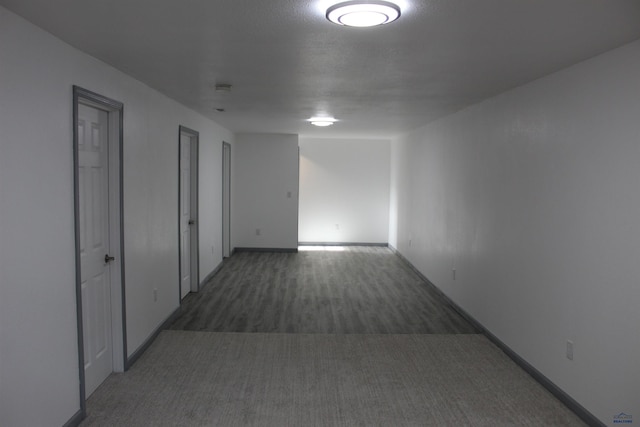 corridor with dark carpet and baseboards