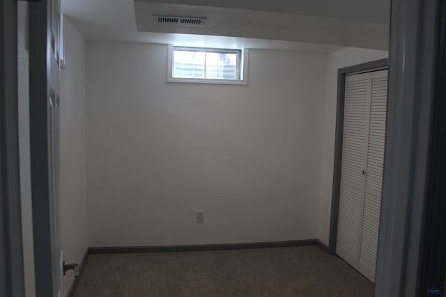 interior space with a closet, visible vents, dark carpet, and baseboards