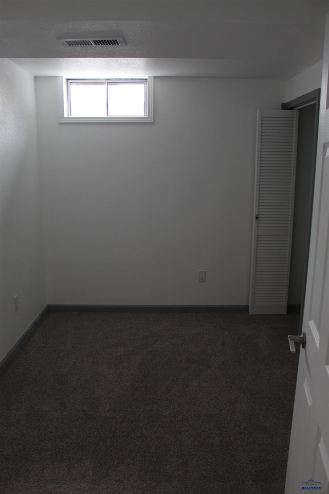 interior space featuring baseboards, visible vents, and dark carpet