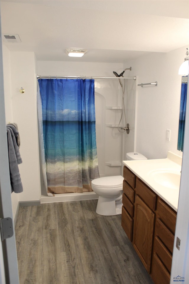 full bath featuring curtained shower, toilet, wood finished floors, visible vents, and vanity