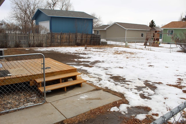 snowy yard featuring fence and a playground