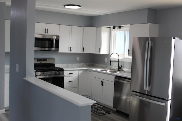 kitchen with a sink, stainless steel appliances, light countertops, and white cabinetry