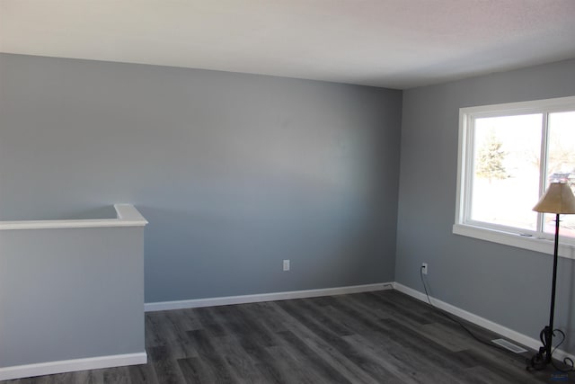 spare room featuring visible vents, dark wood finished floors, and baseboards