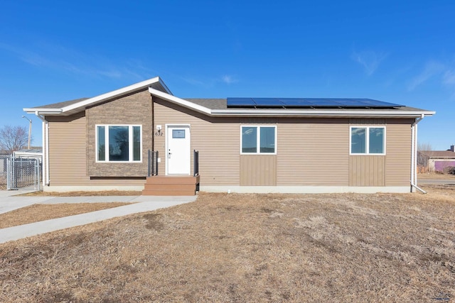 ranch-style house with fence and solar panels