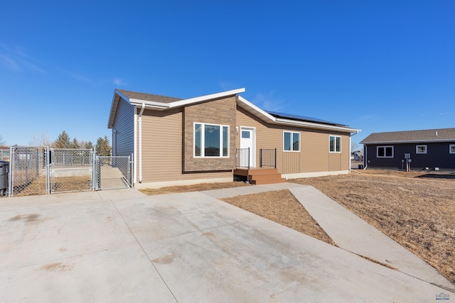 ranch-style house featuring roof mounted solar panels, fence, and a gate