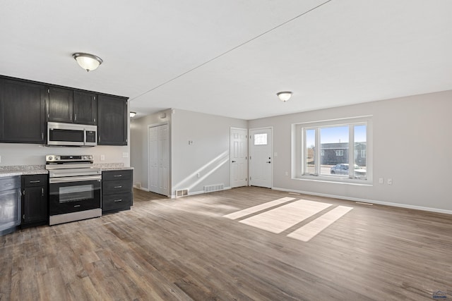 kitchen featuring appliances with stainless steel finishes, open floor plan, light countertops, and light wood-style flooring