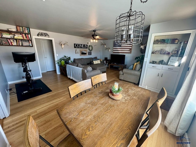 dining space featuring wood finished floors and ceiling fan with notable chandelier