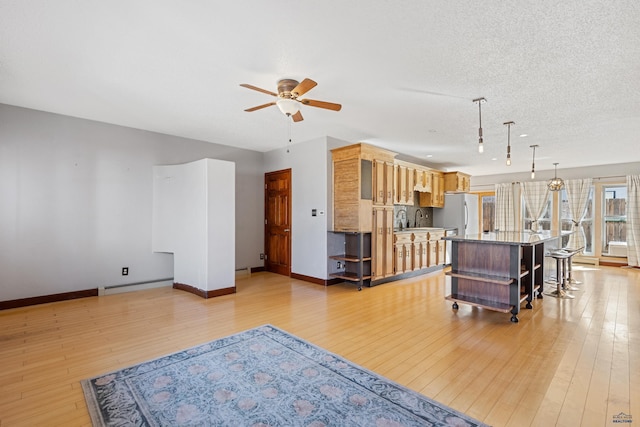 living room with baseboards, a ceiling fan, light wood-style flooring, a textured ceiling, and a baseboard heating unit