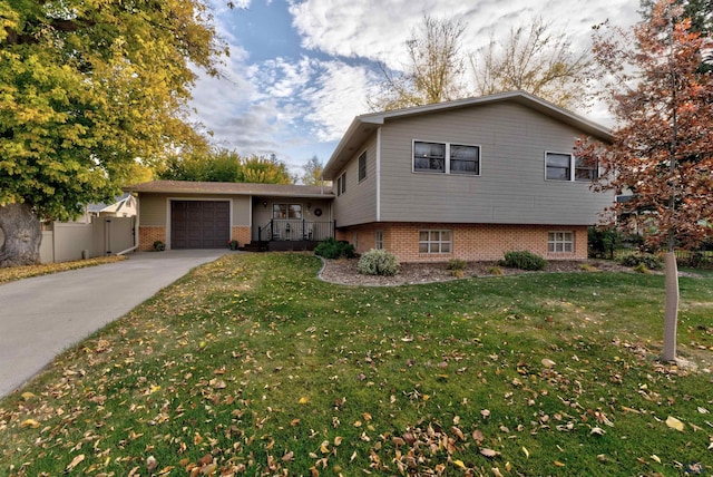 split level home featuring an attached garage, a front lawn, concrete driveway, and brick siding