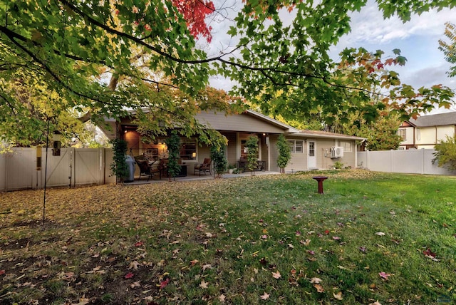 back of property featuring a yard, a gate, a fenced backyard, and a patio