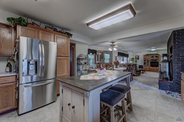 kitchen featuring open floor plan, a breakfast bar, brown cabinetry, and stainless steel refrigerator with ice dispenser