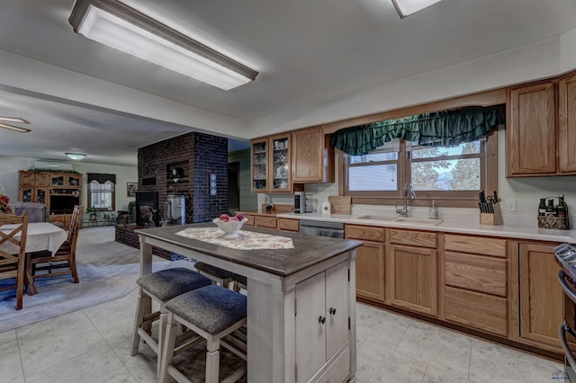 kitchen featuring appliances with stainless steel finishes, glass insert cabinets, brown cabinets, light countertops, and a sink