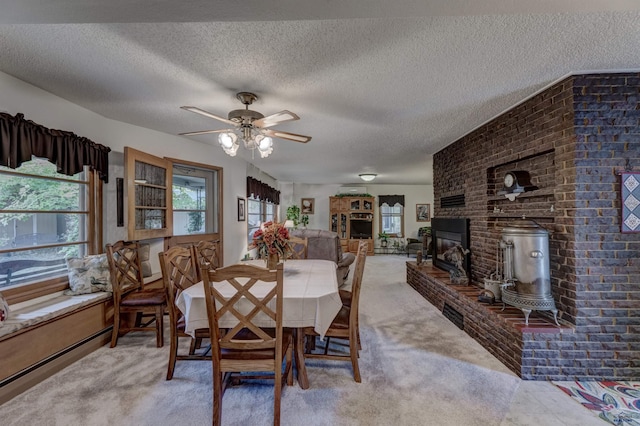 dining space featuring a brick fireplace, ceiling fan, a textured ceiling, and light colored carpet