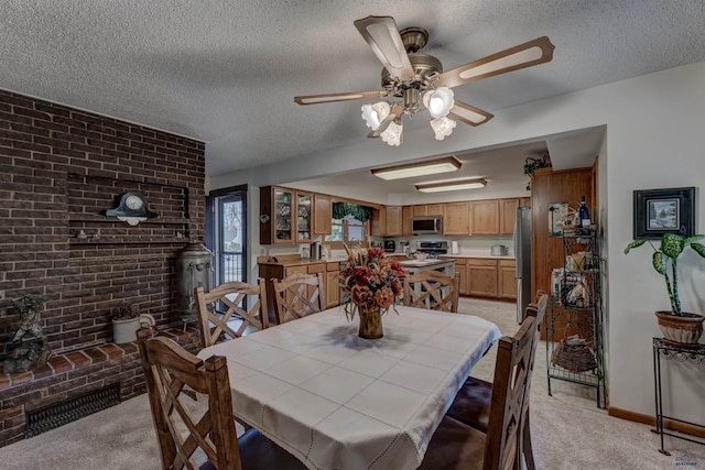 dining area featuring a wood stove, light carpet, a textured ceiling, and brick wall