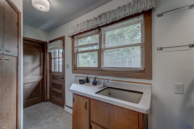 kitchen with brown cabinetry, a baseboard radiator, light countertops, and a sink