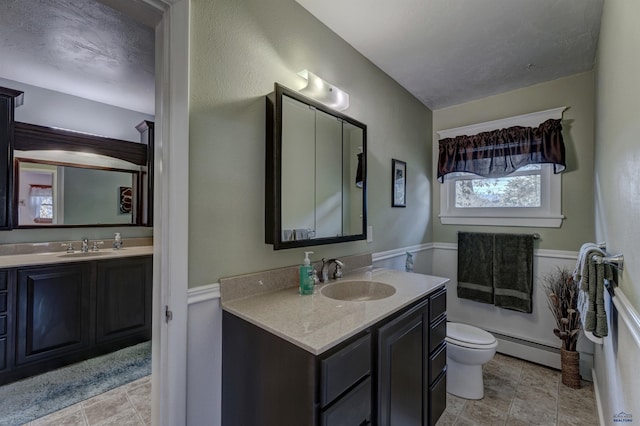 bathroom with toilet, baseboard heating, a textured ceiling, and vanity