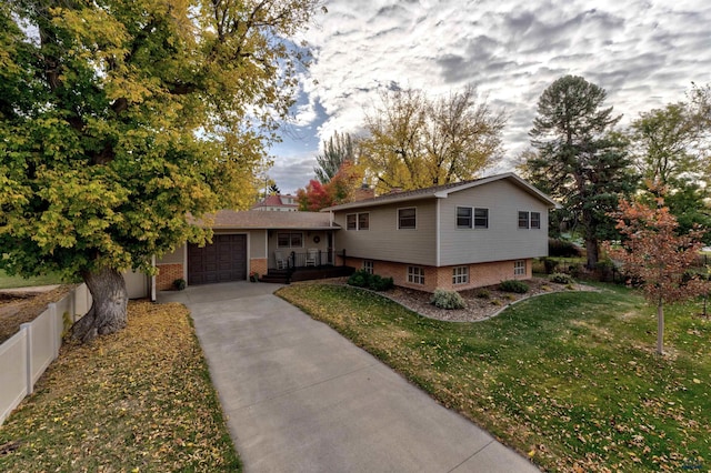 split level home featuring an attached garage, driveway, a front lawn, and brick siding