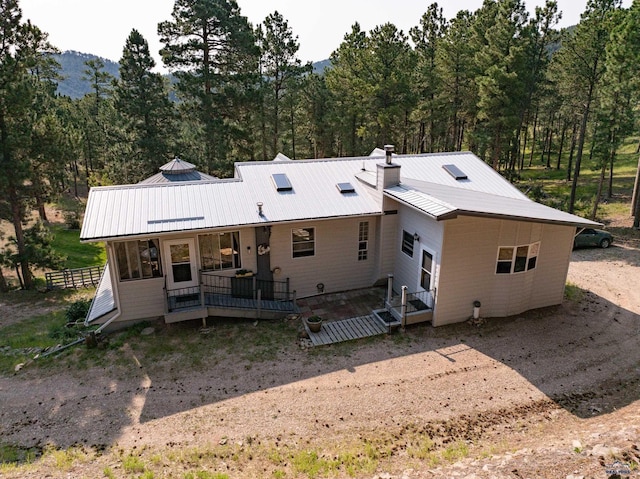 rear view of property with a porch, metal roof, and a chimney